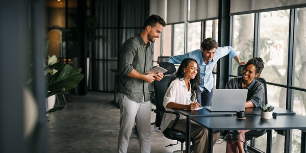 People collaborating around a table talking around a laptop