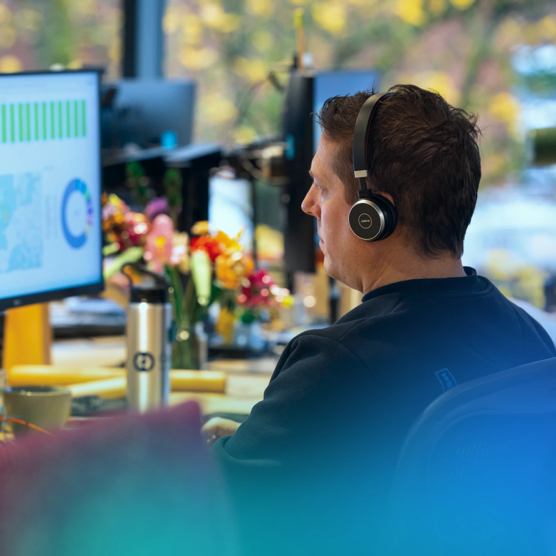 Image of a man sat at a computer looking at charts and wearing a headset